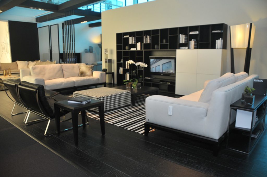 A contemporary open living space with white sofas, black lounge chairs and tall shelving